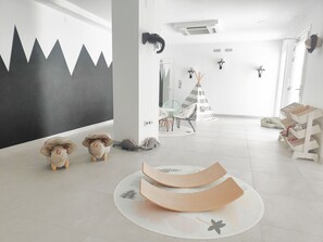 Relax in a serene space with a white floor, a mountain mural, and plush sheep toys.