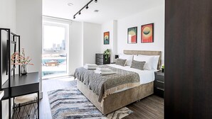 Een moderne slaapkamer met een groot bed, een bureau en uitzicht op de stad.