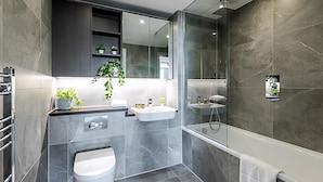 Een moderne badkamer met een grote spiegel, een badkuip, een douche en een toilet.