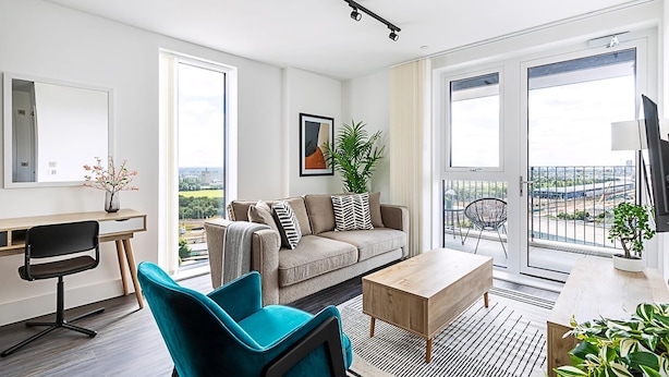 Een moderne woonkamer met een bank, stoelen, een bureau en een balkon met uitzicht op de stad.