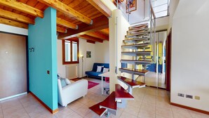 Una sala de estar moderna con una pared azul de acento, un sofá blanco, un sofá azul y una escalera de madera.