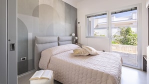 Un dormitorio con una cama grande, una mesita de noche, una ventana y vistas al exterior.