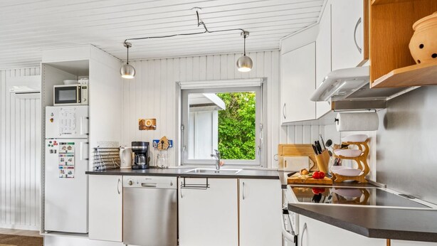 A modern kitchen with white cabinetry, stainless steel appliances, and a window providing a view of greenery outside. - "Mani" - 1.1km from the sea by Interhome (Ebeltoft)