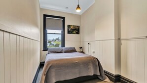 Een slaapkamer met een bed, een raam en een schilderij aan de muur.