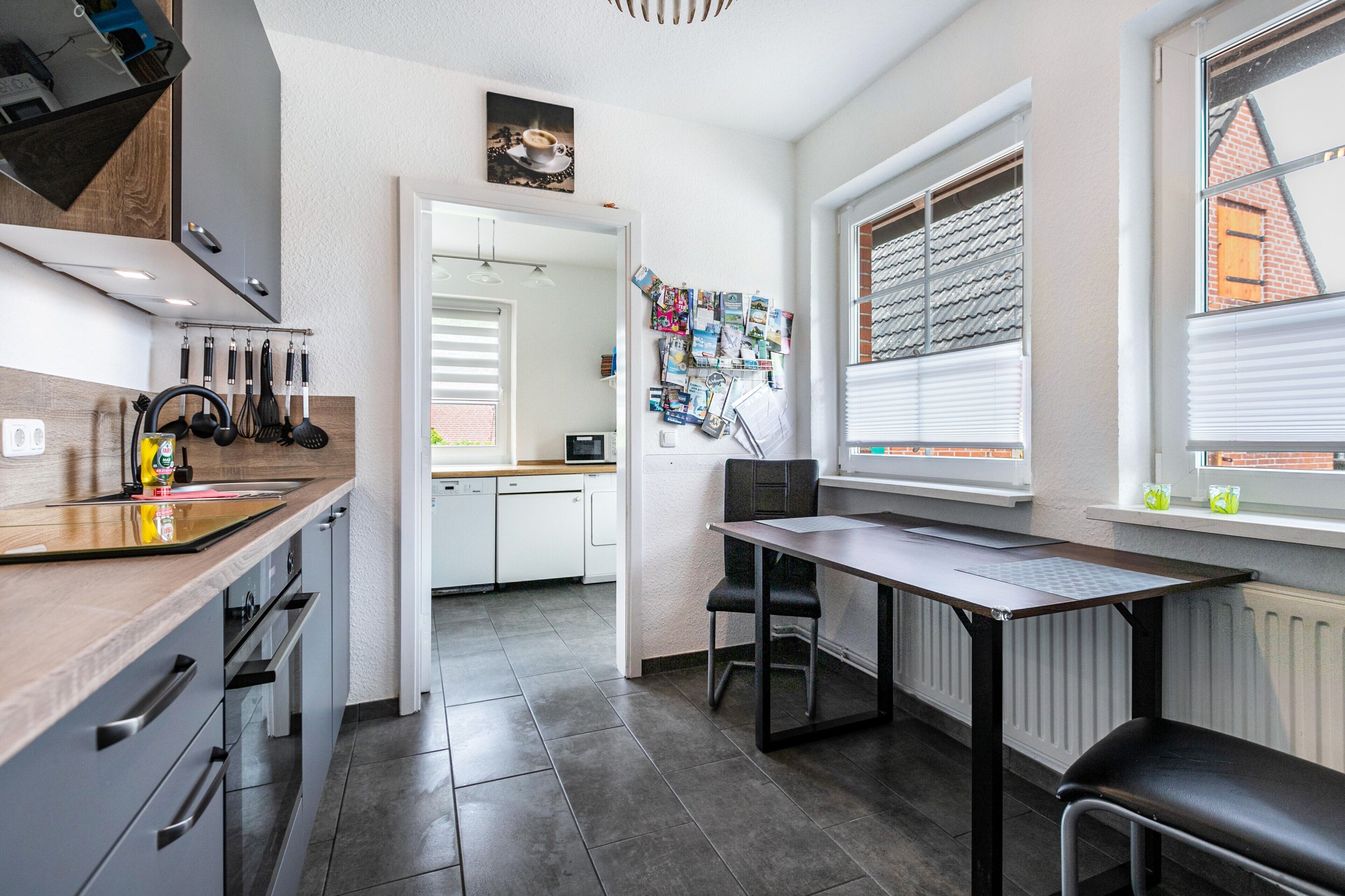 Een moderne keuken met een eethoek, witte kastjes en uitzicht door het raam.