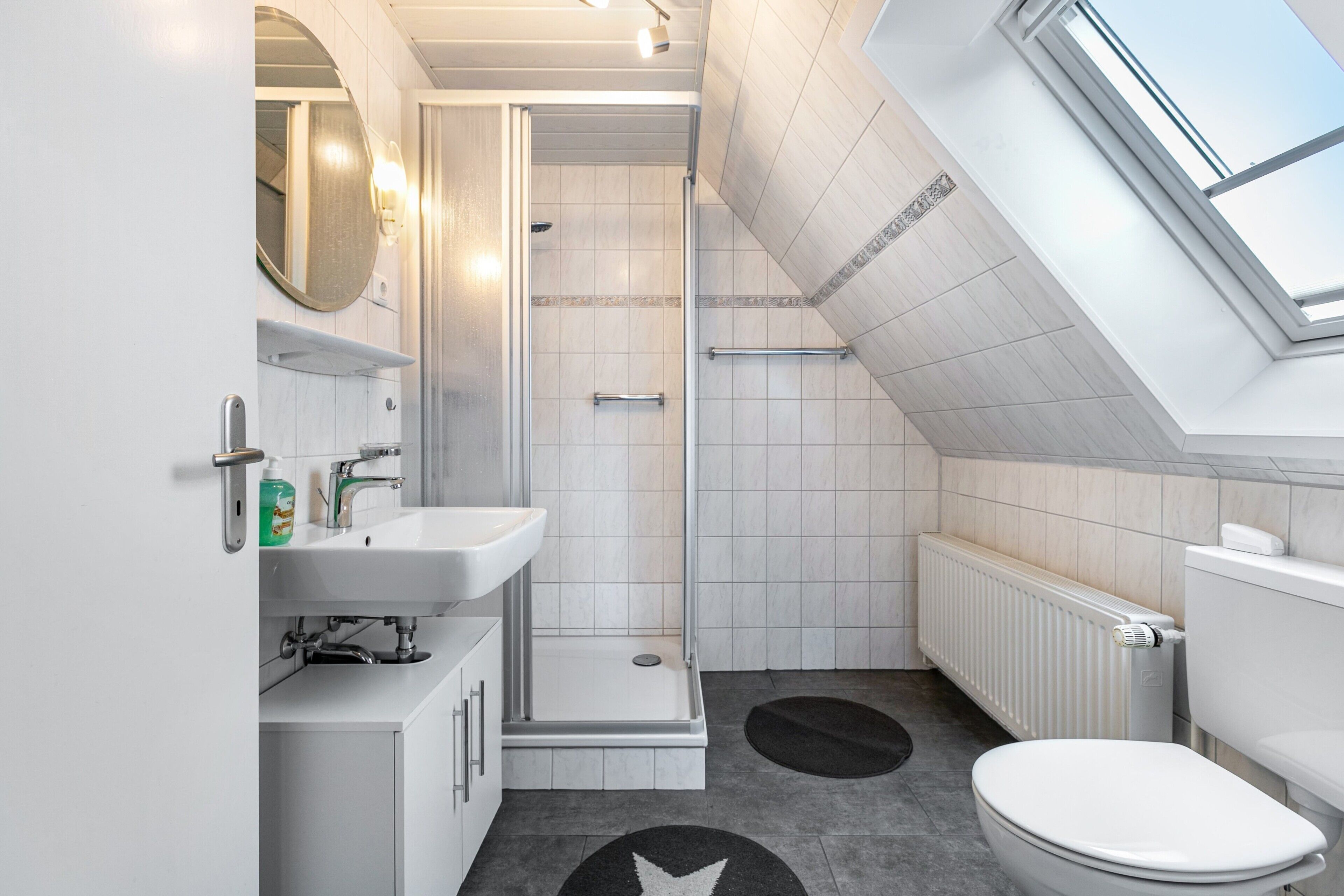 A modern bathroom with a shower, toilet, and sink.
