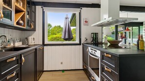 Una cucina compatta con una finestra, una macchina da caffè e una ciotola sul ripiano.