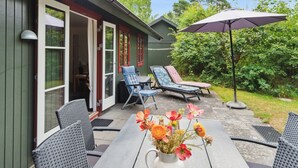 En terrasse med et bord, stole og en blomstervase.