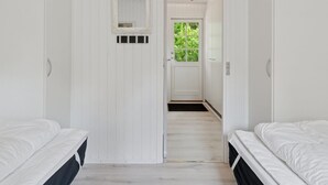 Et soveværelse med to senge, en dør til en balkon og et lille spejl på væggen.