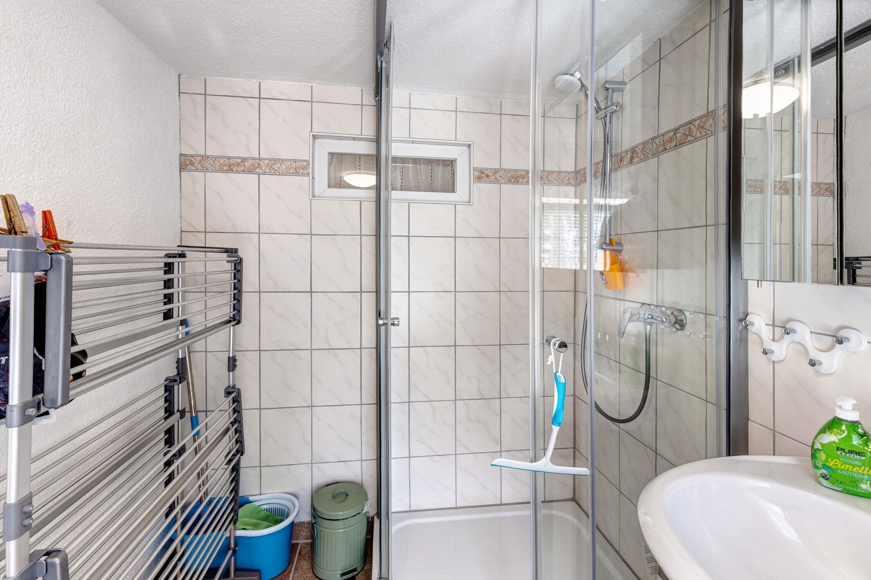 Ein Badezimmer mit einer gläsernen Duschkabine, einem weißen Waschbecken und einem Handtuchhalter.