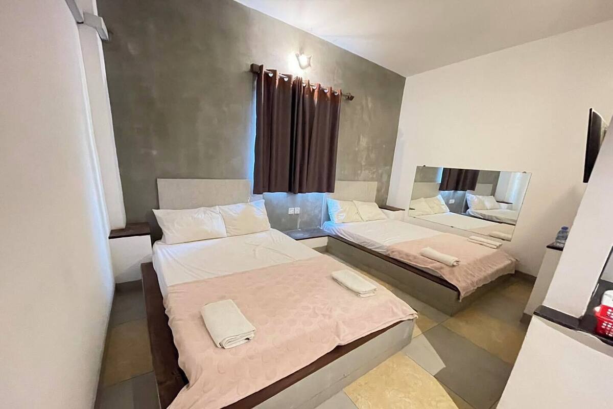 A hotel room with two beds, a large mirror, and a small desk with a water bottle.