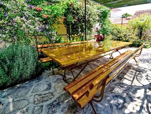 A wooden table with benches in an outdoor garden area with various plants and flowers. - Pažanin by Interhome (Vinišće)