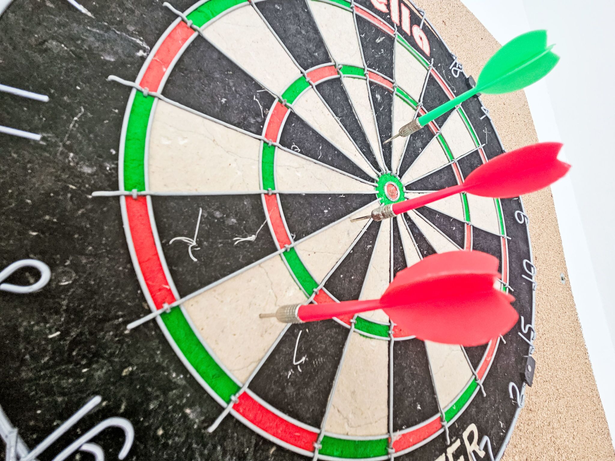 Een dartbord met drie pijlen in het midden, een zwarte achtergrond en cijfers van 1 tot 20.