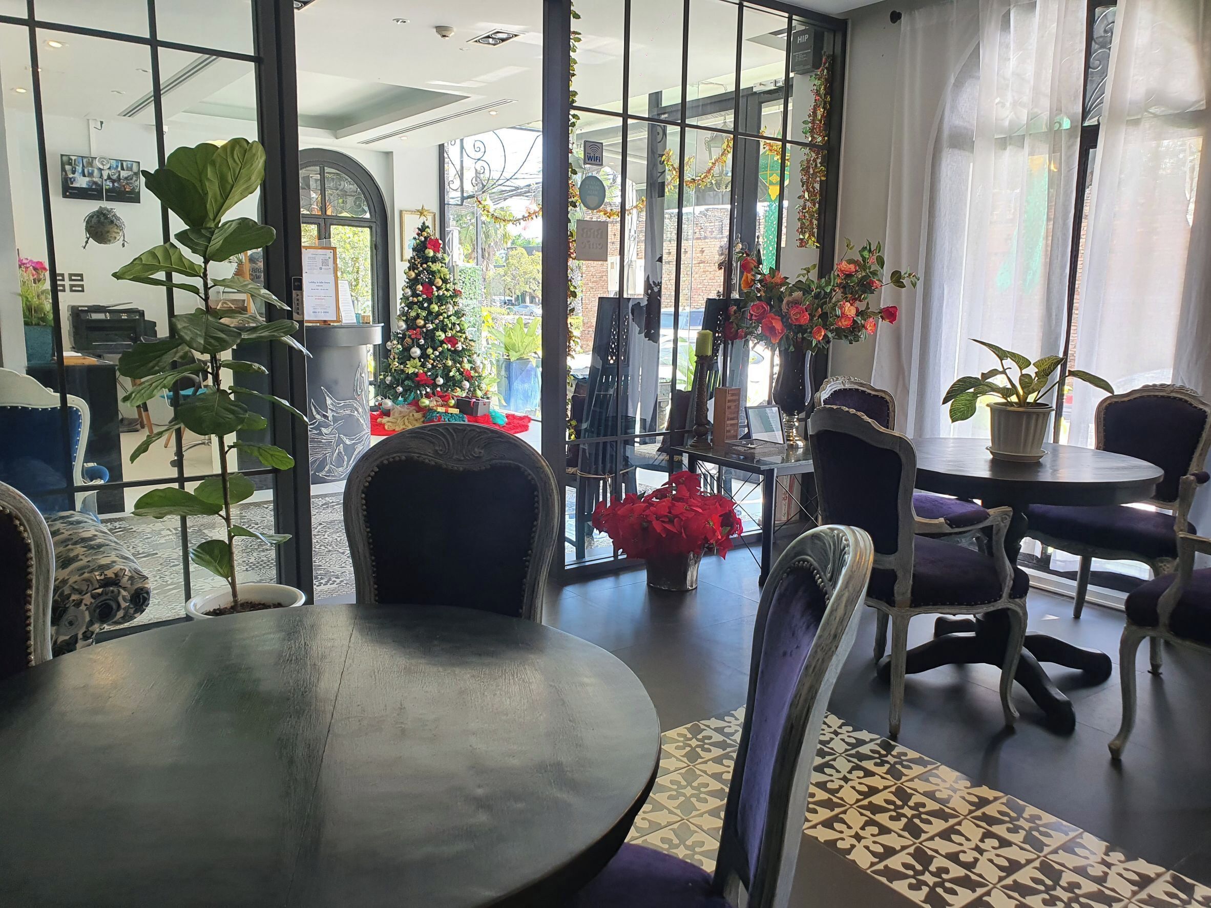 Un interior moderno con una mesa redonda, sillas, un árbol de Navidad y plantas en macetas.