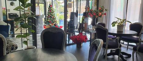 Un interior moderno con una mesa redonda, sillas, un árbol de Navidad y plantas en macetas.