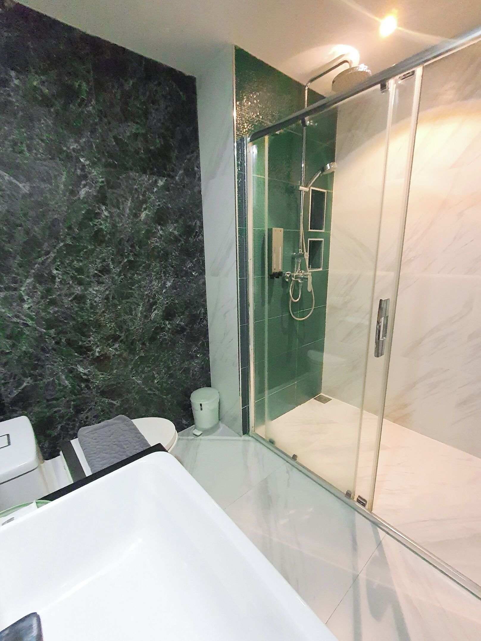 Un baño moderno con ducha de vidrio, una bañera blanca y una pared de mármol.