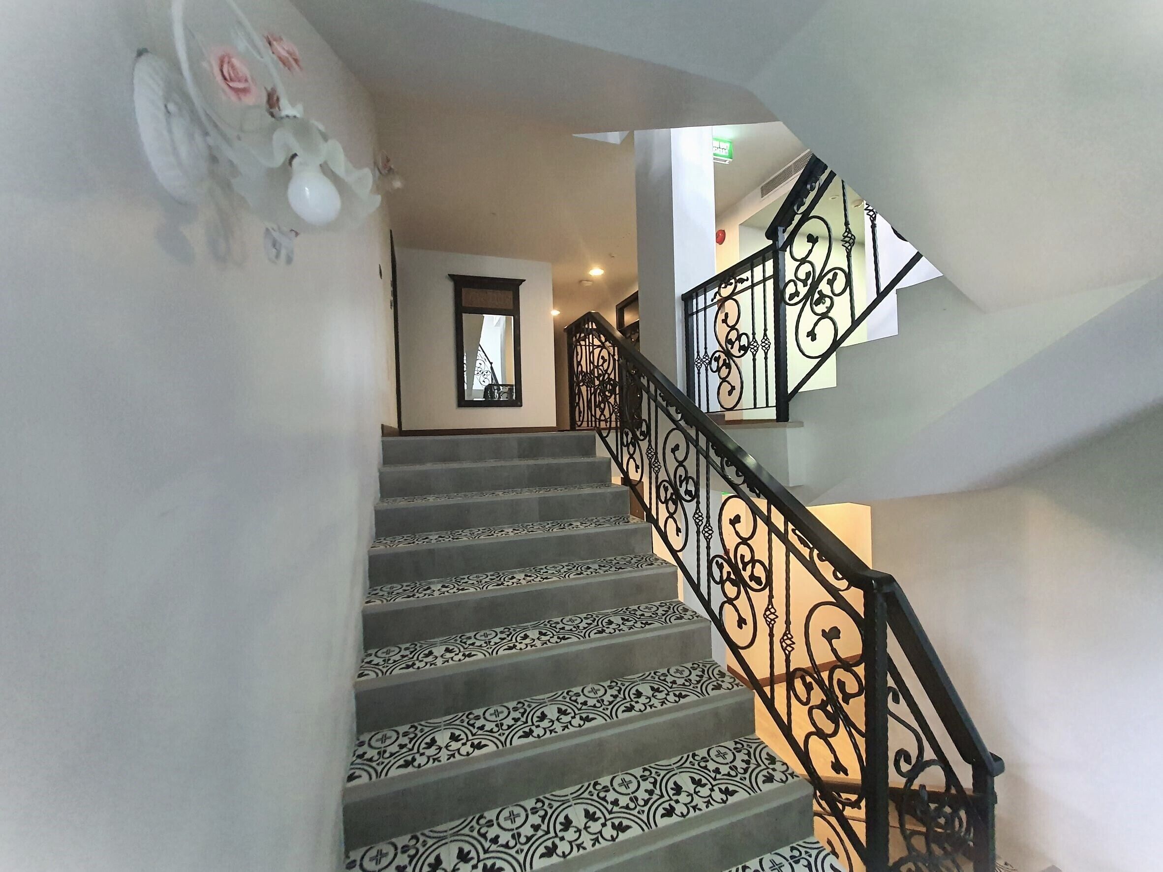 A staircase with patterned carpet and ornate black metal railings.