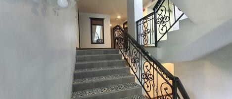 A staircase with patterned carpet and ornate black metal railings.