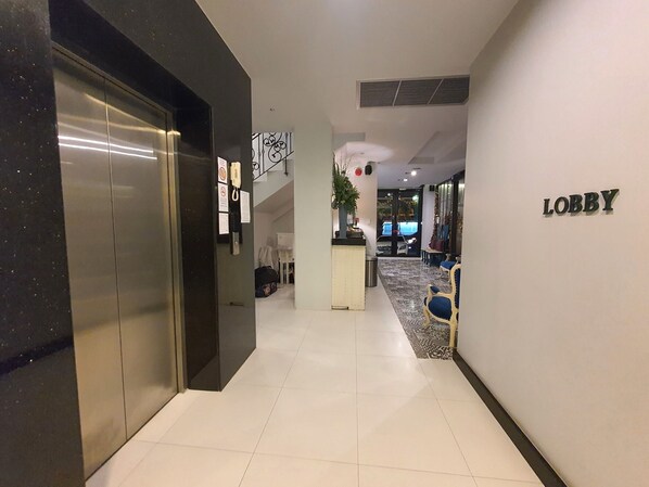 A hotel lobby with a reception desk, seating area, and an elevator. - Marigold Lanna Boutique Hotel (Chiang Mai)
