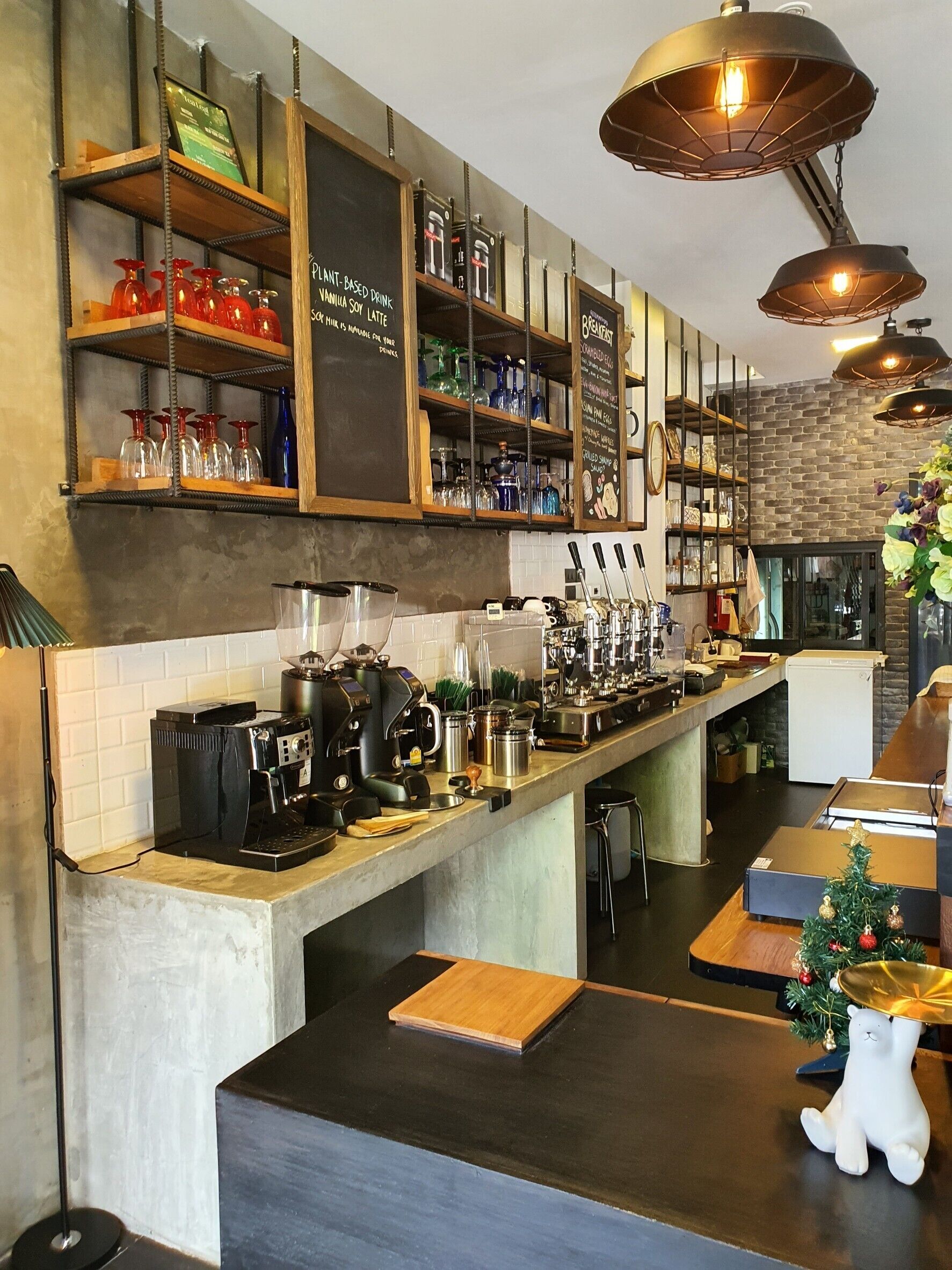 Kahvila, jossa on pitkä palvelutiski, espressokoneita ja hyllyjä, jotka on täytetty erilaisilla tuotteilla.