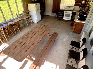 Una cocina con una mesa y sillas de madera, un refrigerador, una estufa y un lavamanos.