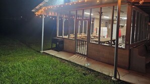 A covered outdoor seating area with string lights, wooden tables, and chairs.