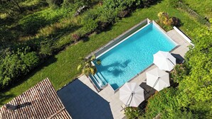 An aerial view of a rectangular swimming pool surrounded by a wooden deck and lush greenery. - Maison Oléa - "Élégance" guest room overlooking the Vézère valley. (Le Bugue)