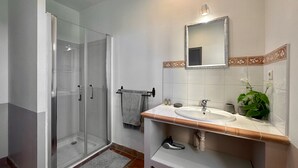 A bathroom with a glass-enclosed shower, a sink with a mirror, and a towel rack. - Maison Oléa - "Élégance" guest room overlooking the Vézère valley. (Le Bugue)