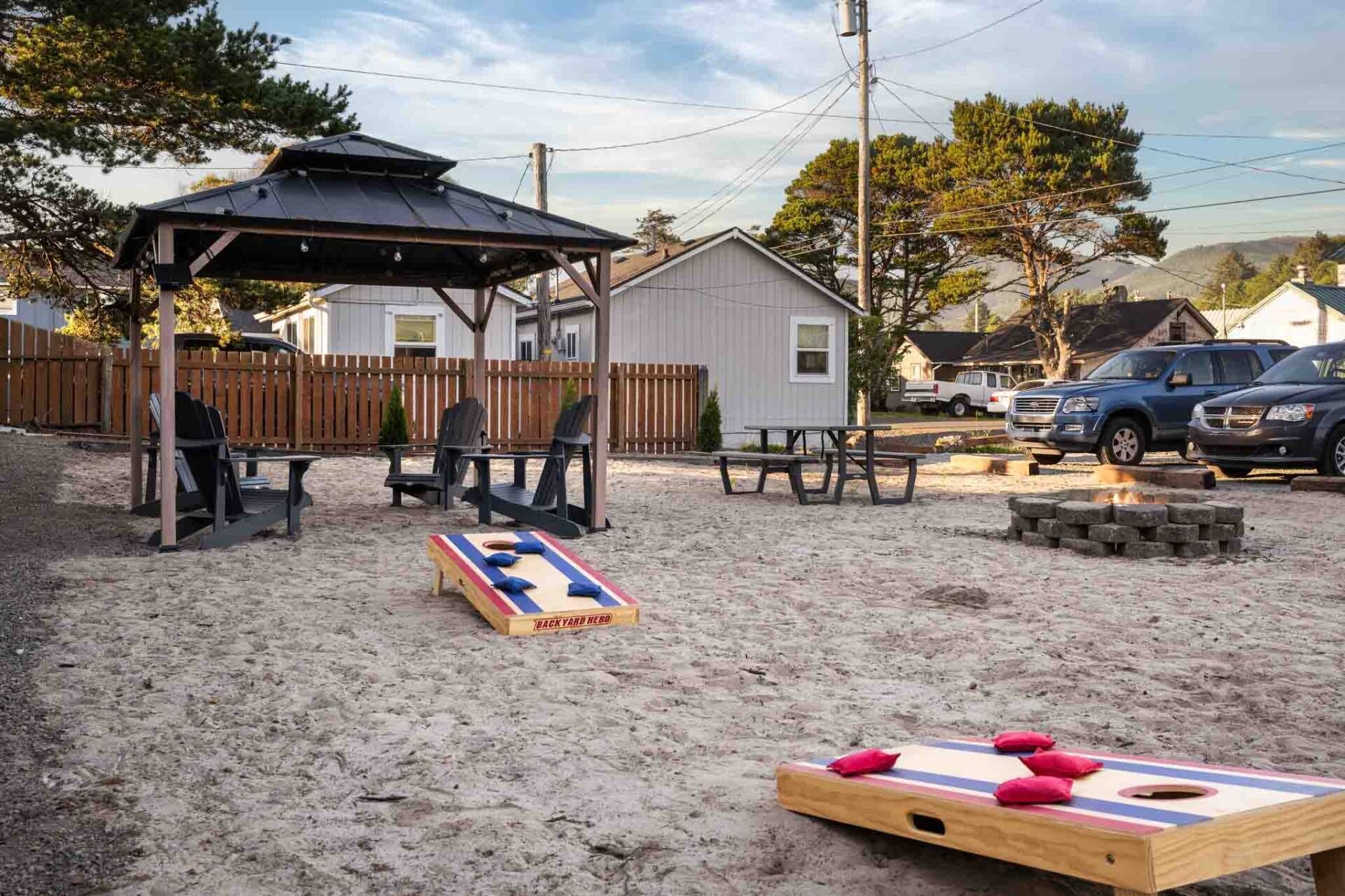 Un jardin avec une terrasse en bois, un abri de jardin en bois, une table de pique-nique et un bac à sable.
