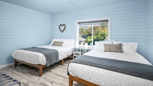 Ein Zimmer mit zwei Betten, einer herzförmigen Dekoration und einem Fenster mit Blick auf Bäume und ein Haus.
