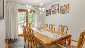 Een eetgedeelte met een houten tafel, stoelen, een kroonluchter en kunstwerken aan de wanden.