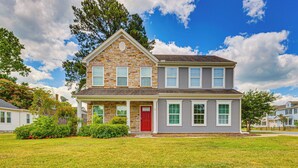 A two-story house with a stone facade, a red door, and a well-maintained lawn. - Fenced Yard & Patio! 2,400-Sq-Ft Chesapeake Home (Chesapeake)