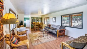 A spacious living room with a sofa, chairs, a coffee table, and a dining area with a table and chairs. - ‘Sunset Cabin’ near Moab w/ Stunning Views! (La Sal)