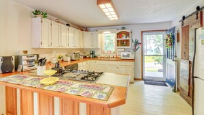 Uma cozinha com armários brancos, uma ilha central e vista para o exterior.