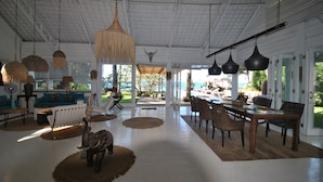 A spacious living area with a high ceiling, large windows, and a view of the outdoors.