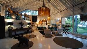 A spacious living area with a high ceiling, large windows, and a variety of seating arrangements.