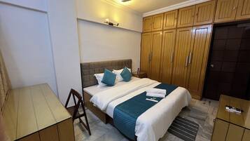 Un dormitorio con cama, armario de madera y escritorio.