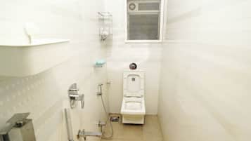 A small, white bathroom with a toilet, a shower, and a window.