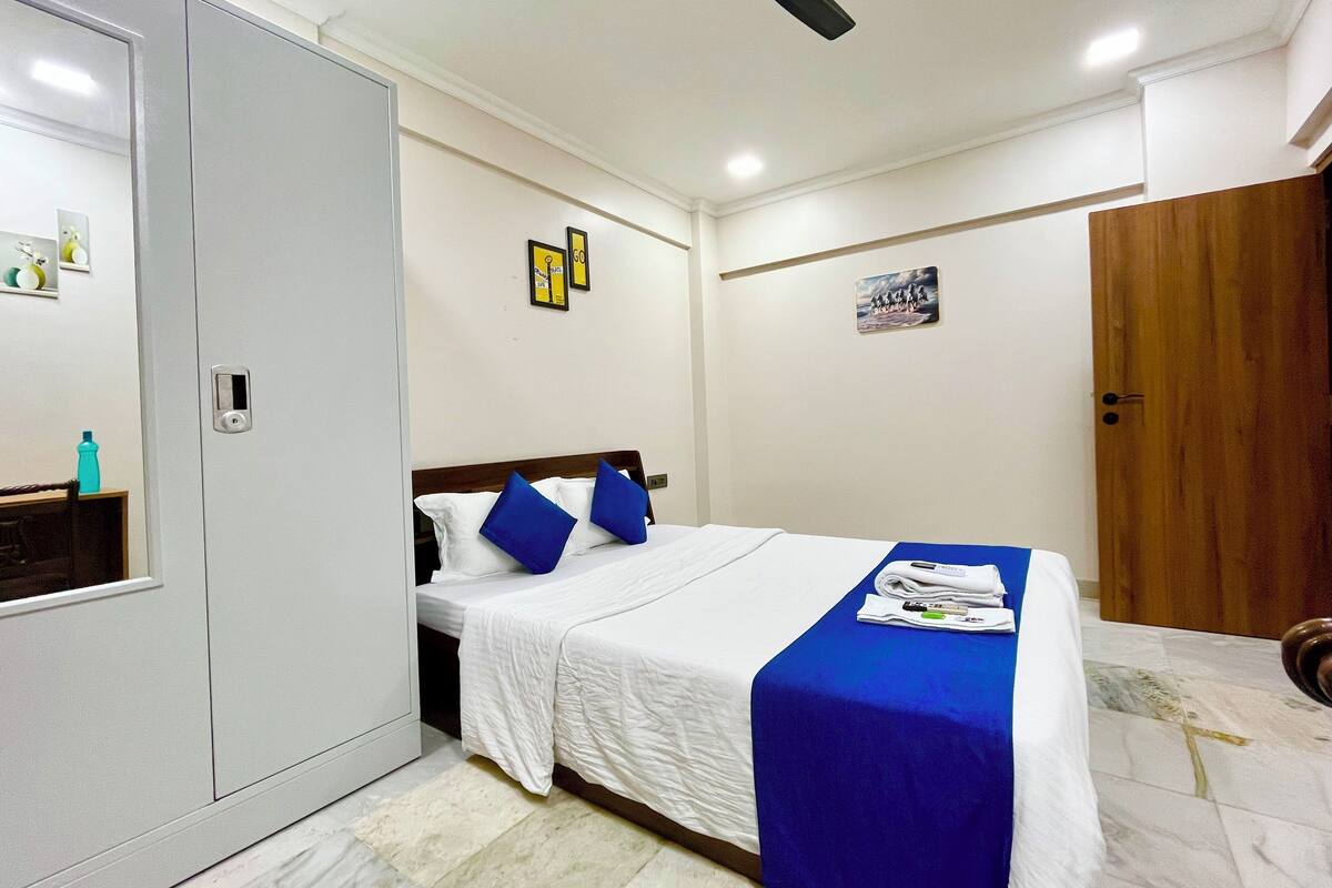 A hotel room with a bed, a wardrobe, a ceiling fan, and a door.