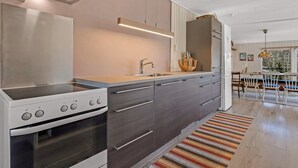A modern kitchen with a built-in oven, a stainless steel range, and a large island with a sink. - "Lovisa" - 7km from the sea by Interhome (Rønde)