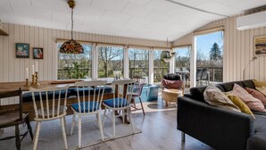 A spacious room with a dining area, a sofa, and a large window providing a view of the outdoors. - "Lovisa" - 7km from the sea by Interhome (Rønde)