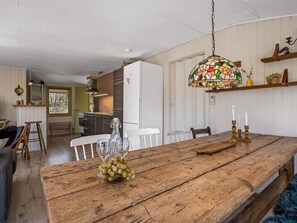 Une cuisine spacieuse avec une table à manger en bois, un luminaire suspendu et une vue sur la salle à manger adjacente.