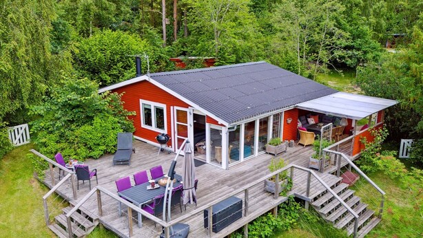 A two-story wooden house with a deck, a covered patio, and a large window overlooking a forested area. - "Lovisa" - 7km from the sea by Interhome (Rønde)