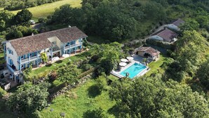 Une grande maison avec une piscine, entourée d’une végétation luxuriante.