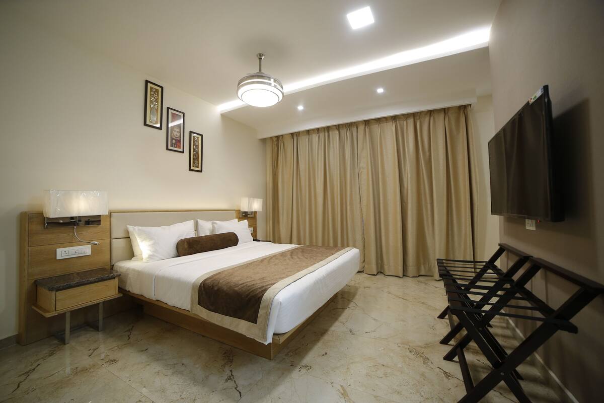 A hotel room with a large bed, bedside tables, a flat-screen TV, and a ceiling fan.