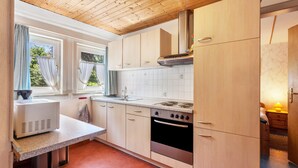 A kitchen with wooden cabinets, a stove, and a window with curtains. - Apartment 'Wohnung 2 Linde' with Balcony and Wi-Fi (Willingen (Upland))