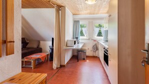 A compact kitchen with a microwave, sink, and stove, a small dining area with a table and chairs, and a cozy seating area with a sofa. - Apartment 'Wohnung 2 Linde' with Balcony and Wi-Fi (Willingen (Upland))