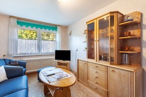 Un salon comprenant un canapé, une table basse, un téléviseur et un meuble en bois doté de portes en verre.