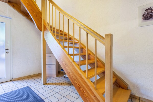 A wooden staircase with a handrail, a white door, a small desk, and a framed picture on the wall. - Holiday Apartment '3 Kirsche' with Mountain View, Shared Garden and Wi-Fi (Willingen (Upland))