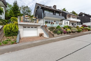 Eine Wohnstraße mit modernen Häusern, einer Garage und einem gepflegten Garten.